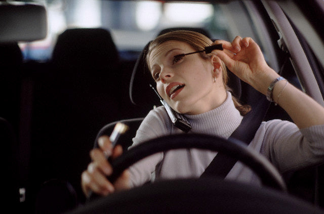 woman driving while applying makeup