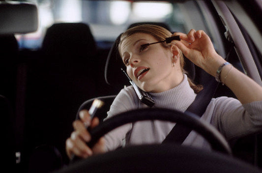 woman driving while applying makeup